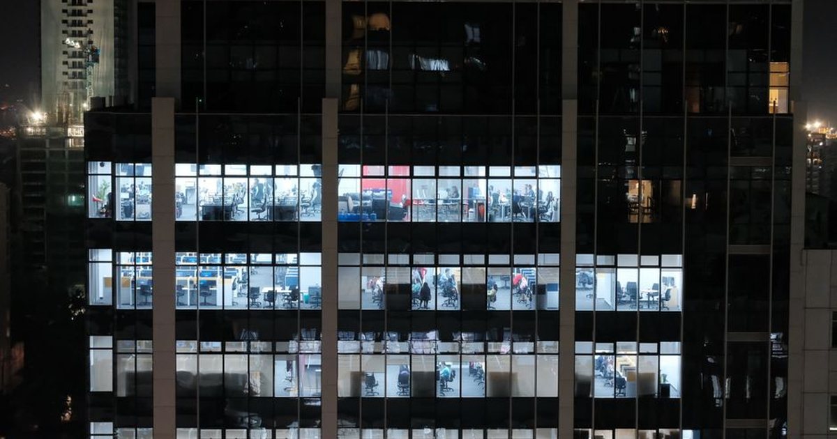 Fachada de un edificio de oficinas moderno con ventanas iluminadas de noche