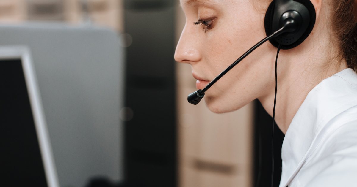 Persona de perfil con auriculares y micrófono trabajando frente a un ordenador