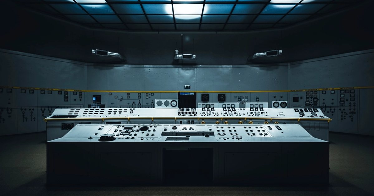 Salle de contrôle industrielle avec panneaux de commande et écrans aux tons bleutés