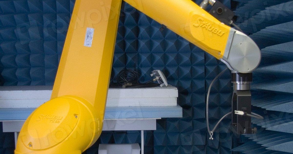 Brazo robótico industrial de color amarillo en una sala insonorizada