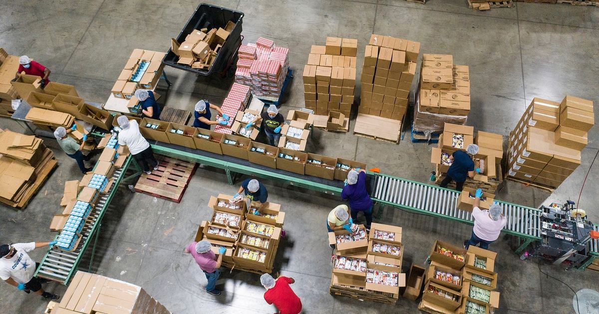 Vista aérea de trabajadores empaquetando cajas en una cinta transportadora en un almacén