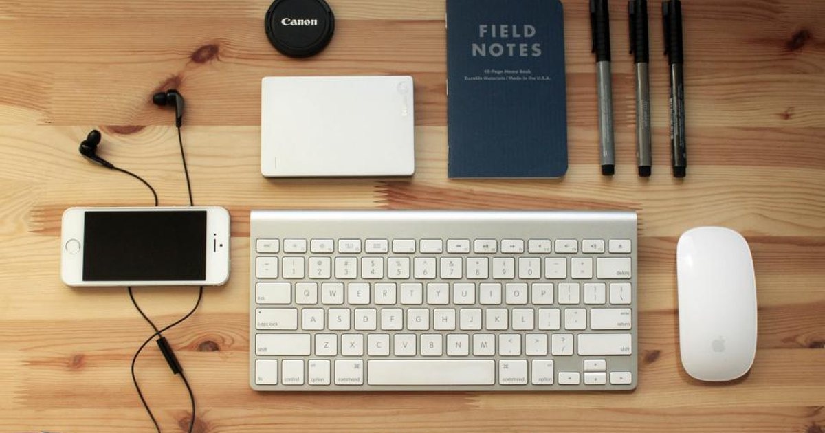 Distribución de accesorios y dispositivos electrónicos ordenados sobre una mesa de madera
