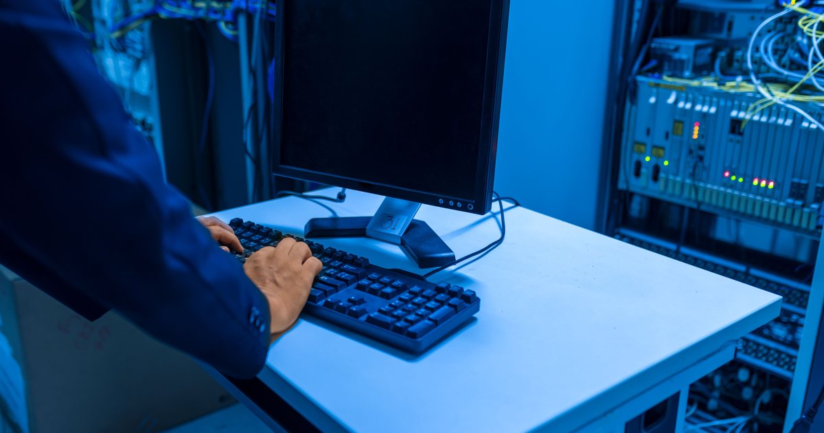 Persona ante una consola de control en una sala técnica iluminada en azul