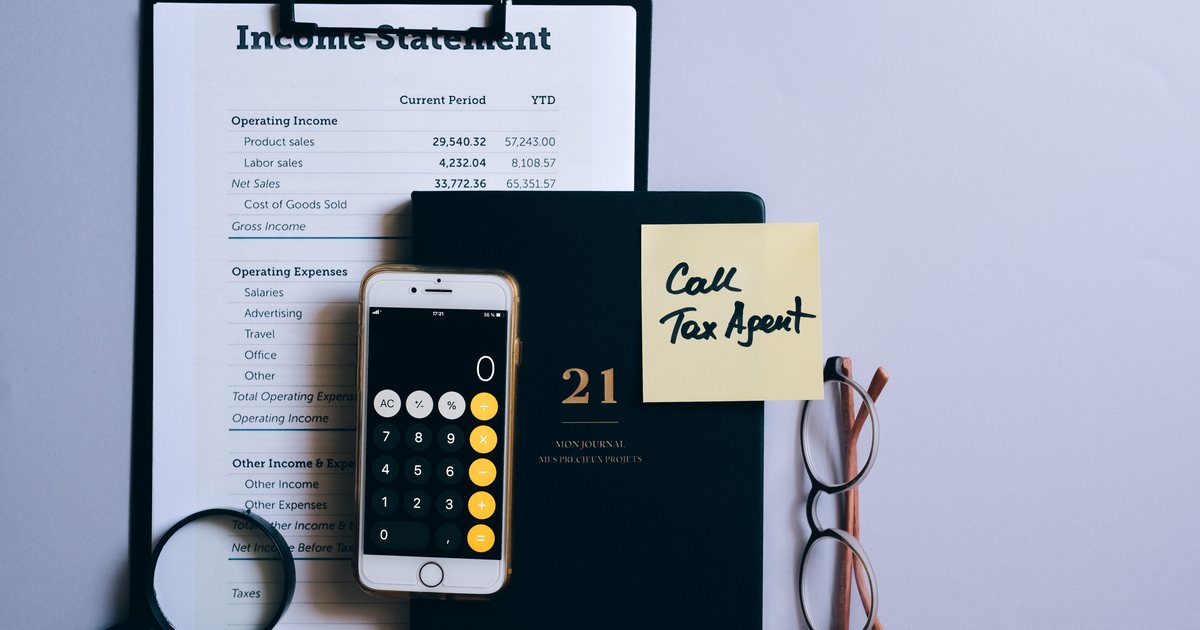 Mesa con una cuenta de resultados impresa, un móvil con la calculadora y una nota adhesiva