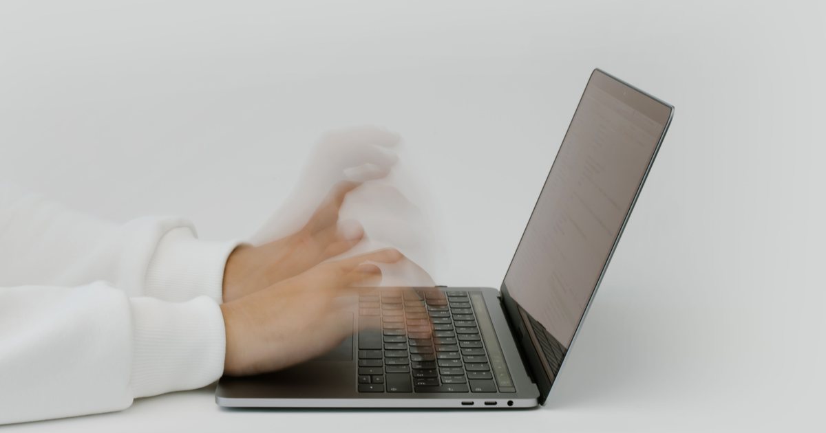 Manos escribiendo con rapidez en el teclado de un portátil