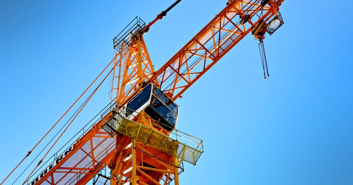 Grúa de construcción de color naranja contra un cielo azul despejado