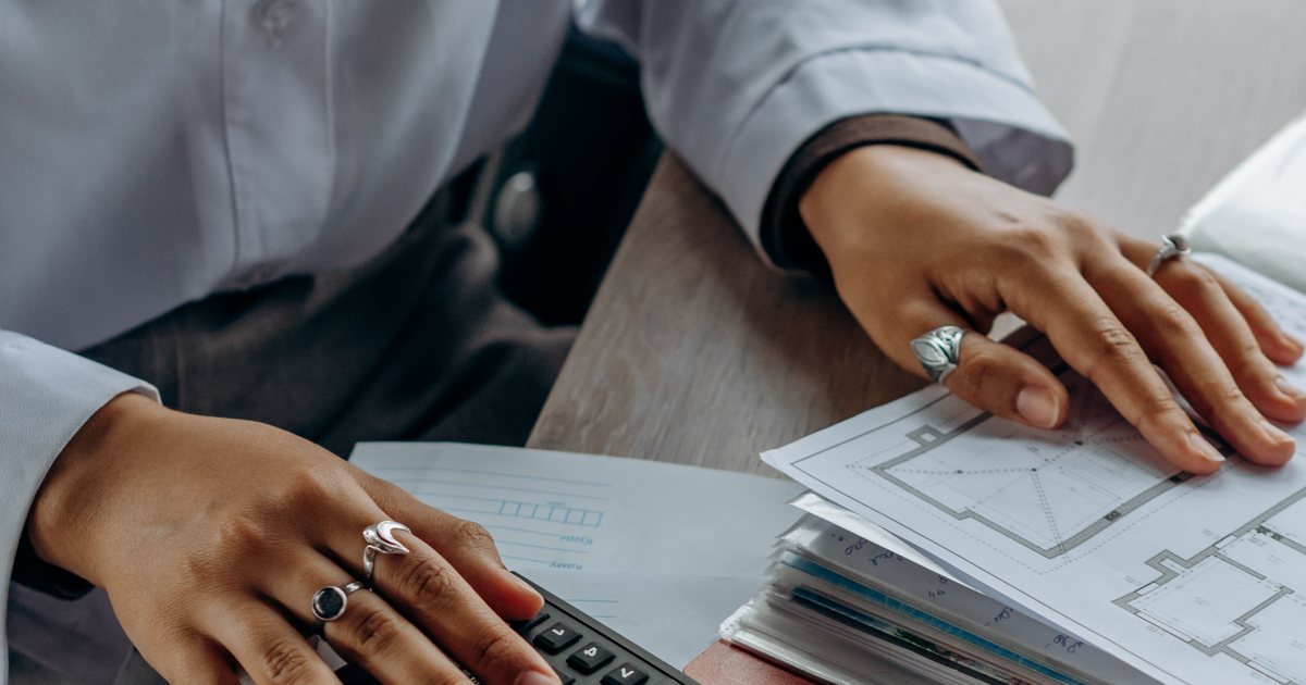 Manos usando una calculadora junto a documentos fiscales sobre una mesa de trabajo