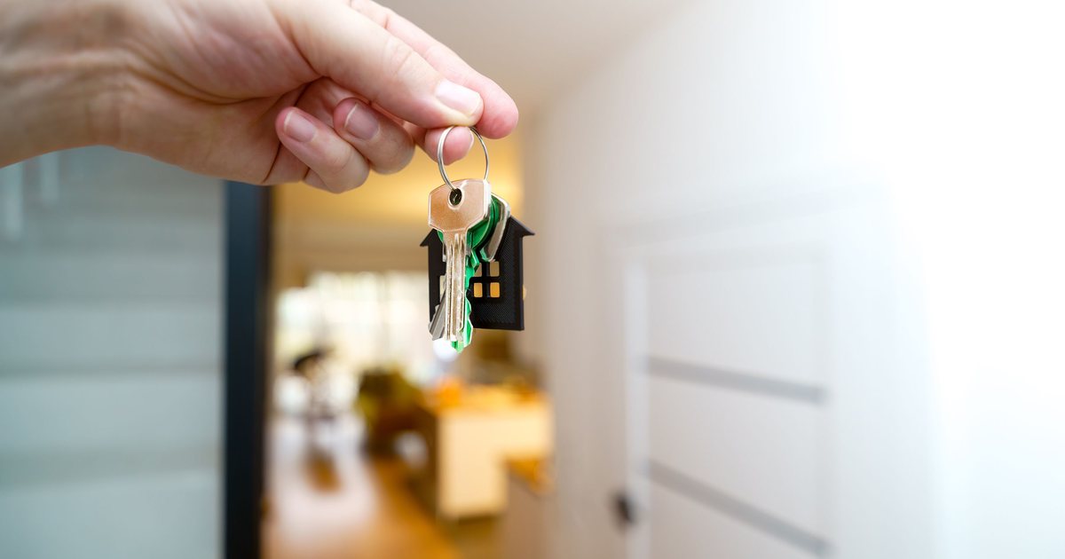 Mano sosteniendo las llaves de una vivienda en el interior de un piso moderno