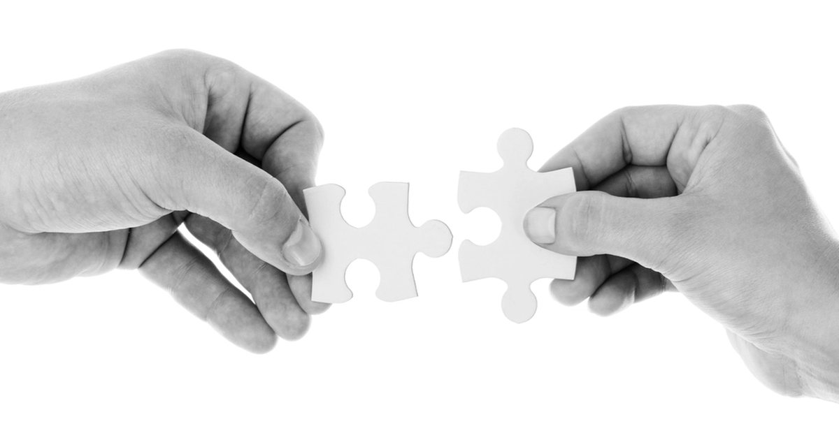 Dos manos encajando una pieza de puzzle, en blanco y negro