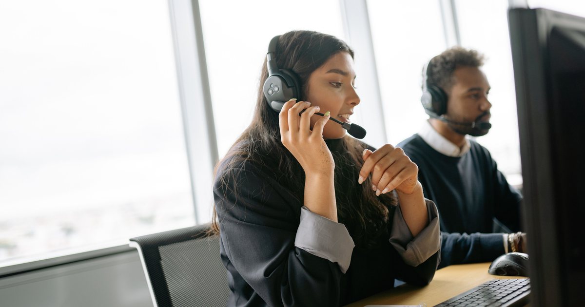 Dos personas con auriculares atendiendo llamadas en una oficina