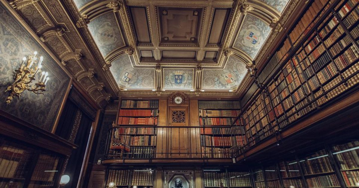 Interior de una biblioteca con cúpula y estanterías de libros, luz cálida