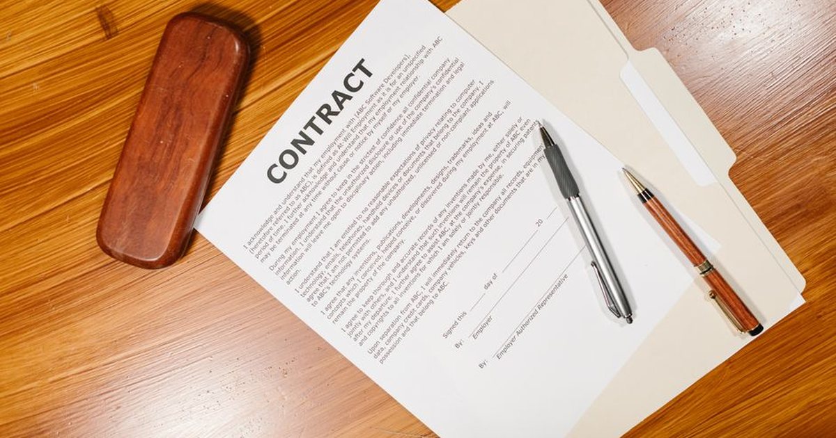 Documento de contrato sobre un escritorio de madera junto a un sello y una pluma