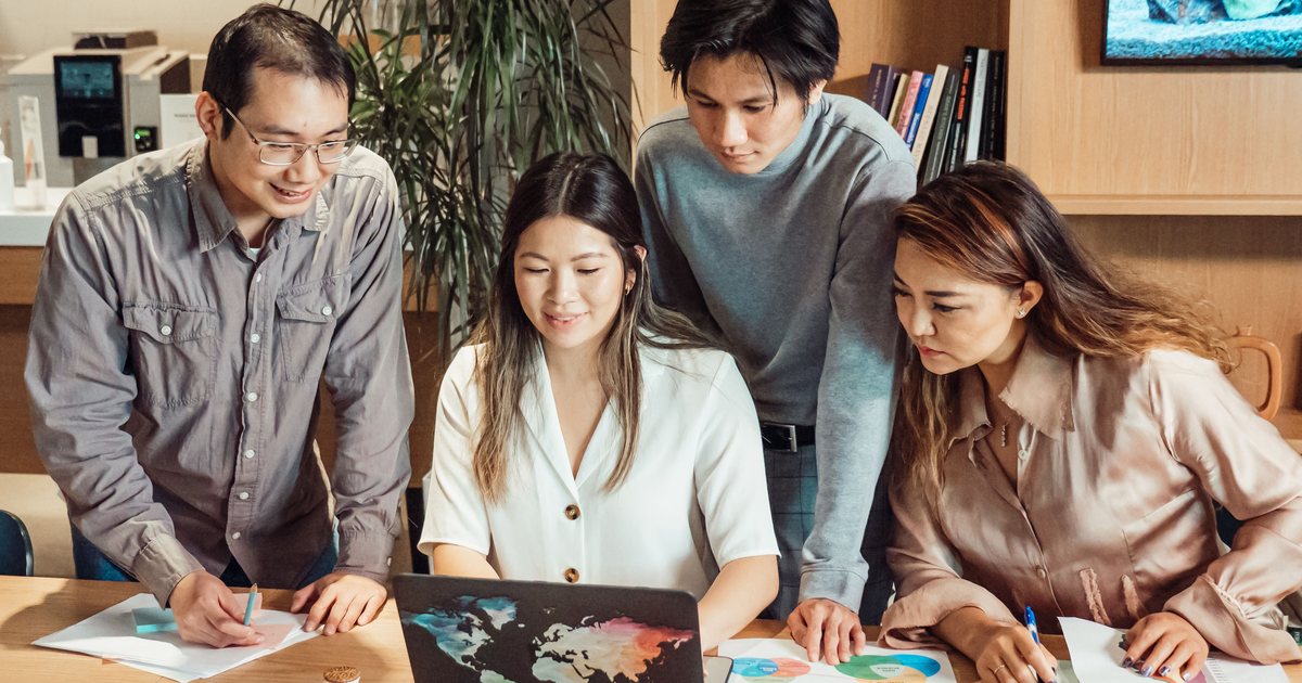 Team of four people reviewing data together on a laptop screen